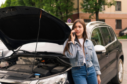 Jovem encostada no carro com celular nas mãos